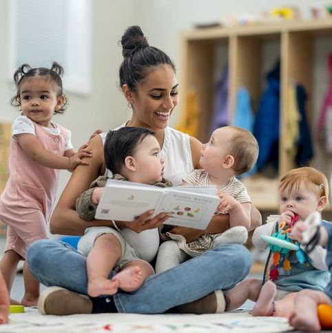 Childcare giver with children in playroom.